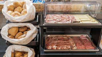 Un buffet proposant une variété de plats, notamment des pâtisseries, des viandes et des fromages.