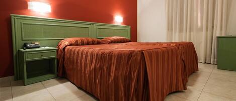 A room with a bed, green nightstand, and two wall-mounted lights.