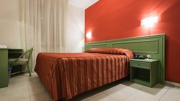 A room with a bed, a nightstand, a chair, and a desk.