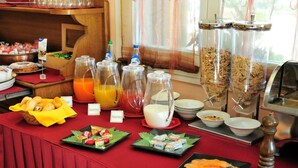 Een buffet met diverse gerechten, waaronder fruit, vruchtensappen en ontbijtgranen.