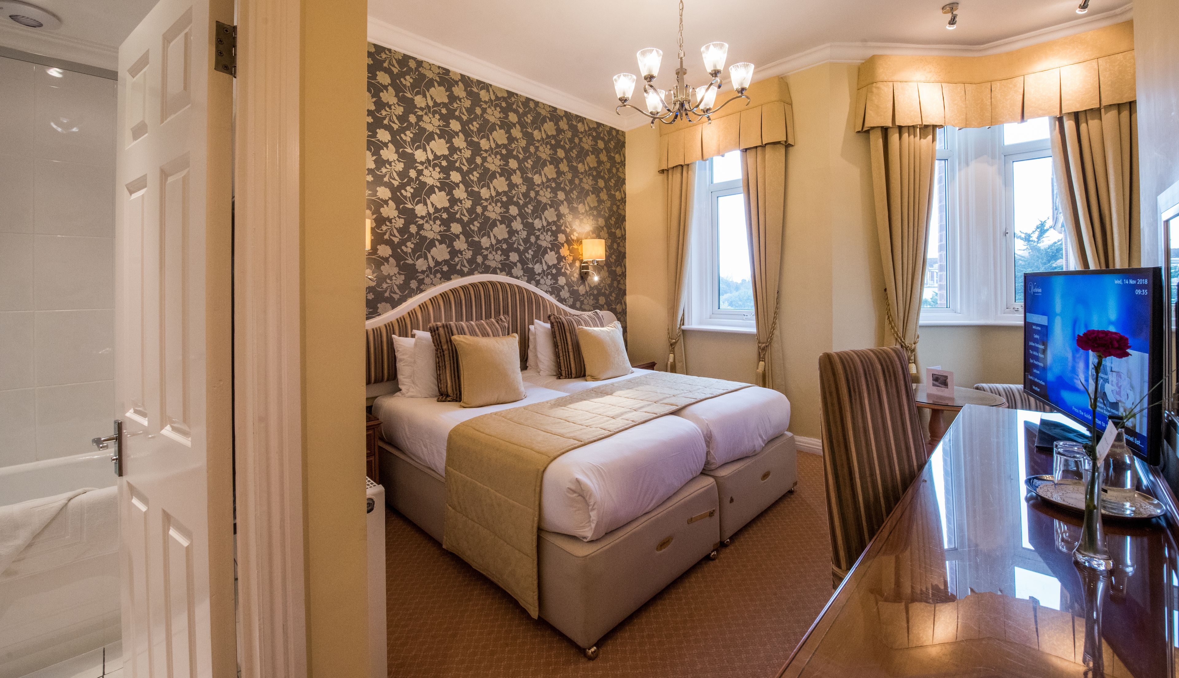 Een hotelkamer met een groot bed, een bureau met een computer en uitzicht op de omgeving.