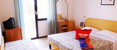 Habitación de hotel con dos camas, un escritorio, una silla, un televisor y una ventana con cortinas.