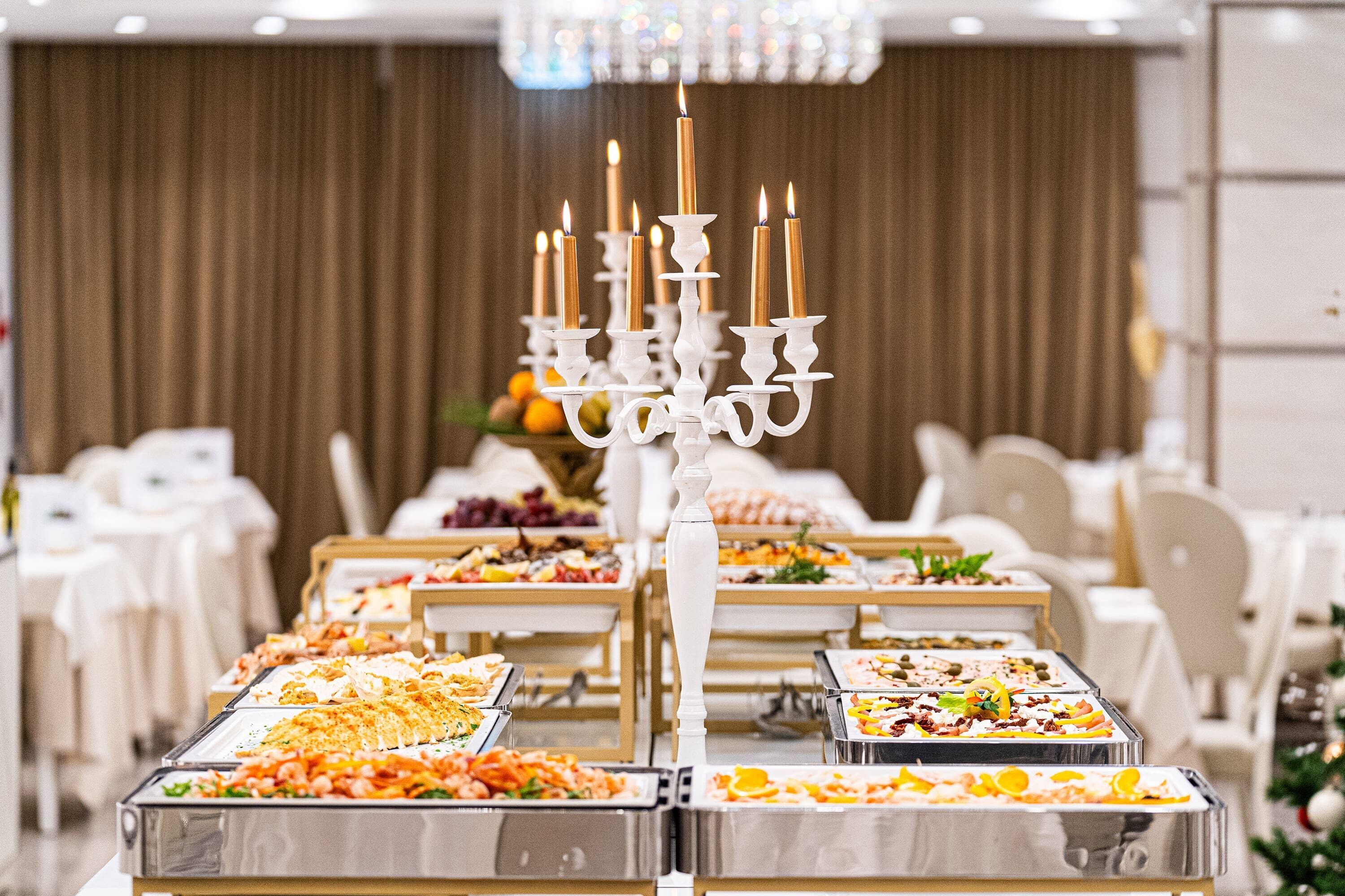 Montaje tipo bufé con varias estaciones de comida y una candelabro central.