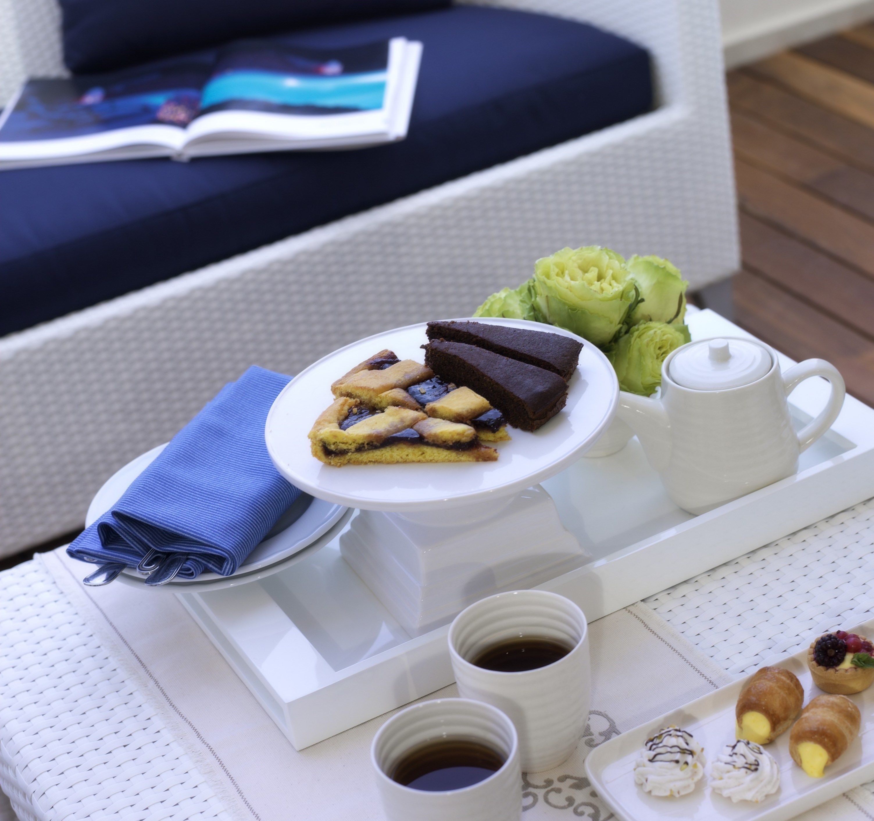Uma bandeja com uma fatia de bolo, uma xícara de café e doces sobre uma mesa.