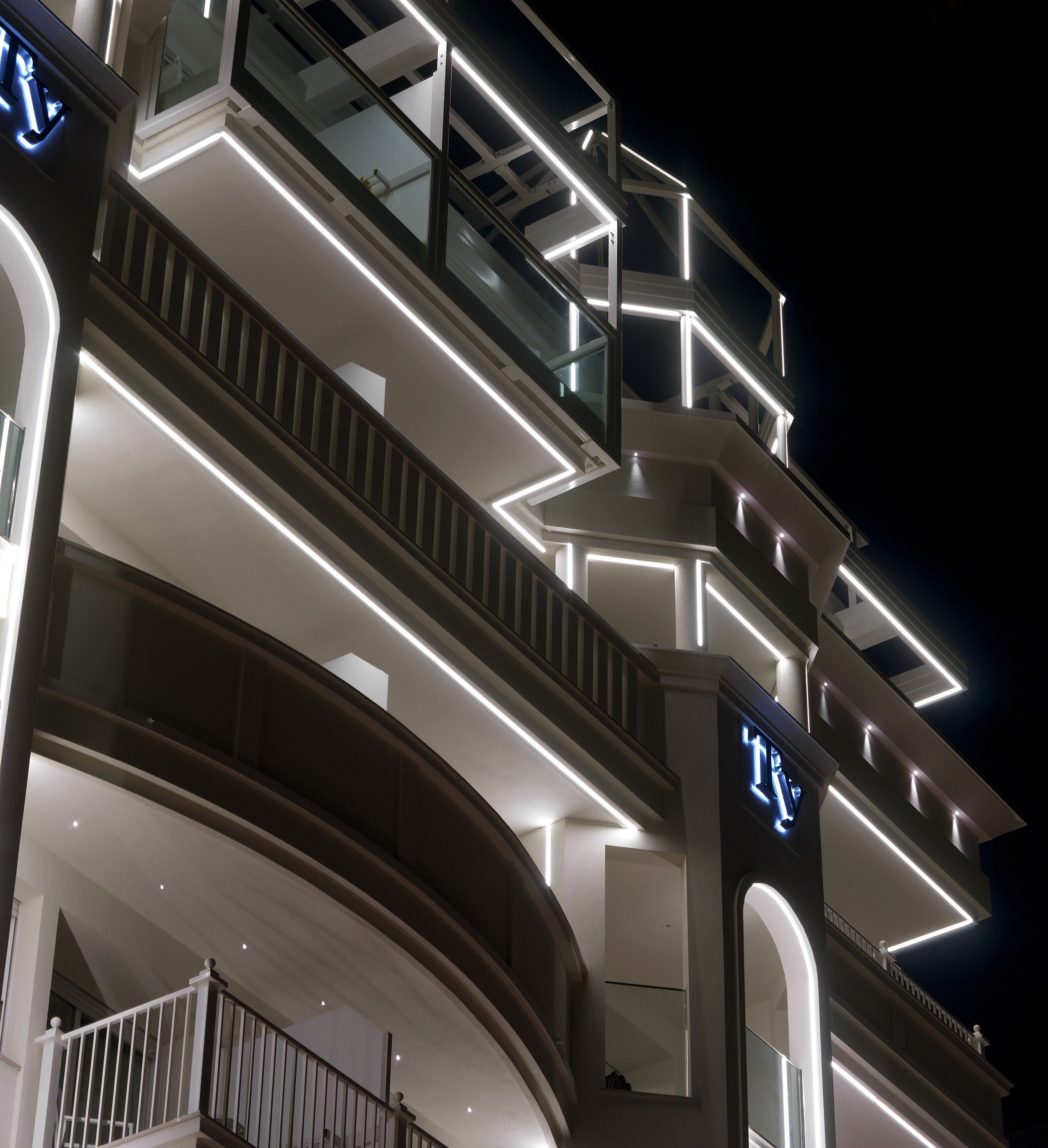 Un hôtel à plusieurs étages, doté de rampes illuminées et d’un balcon en verre.