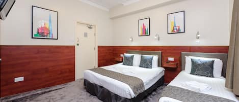 Ein Hotelzimmer mit zwei Betten, einem Holzkopfteil, einem Flachbildfernseher und Bildern an den Wänden.