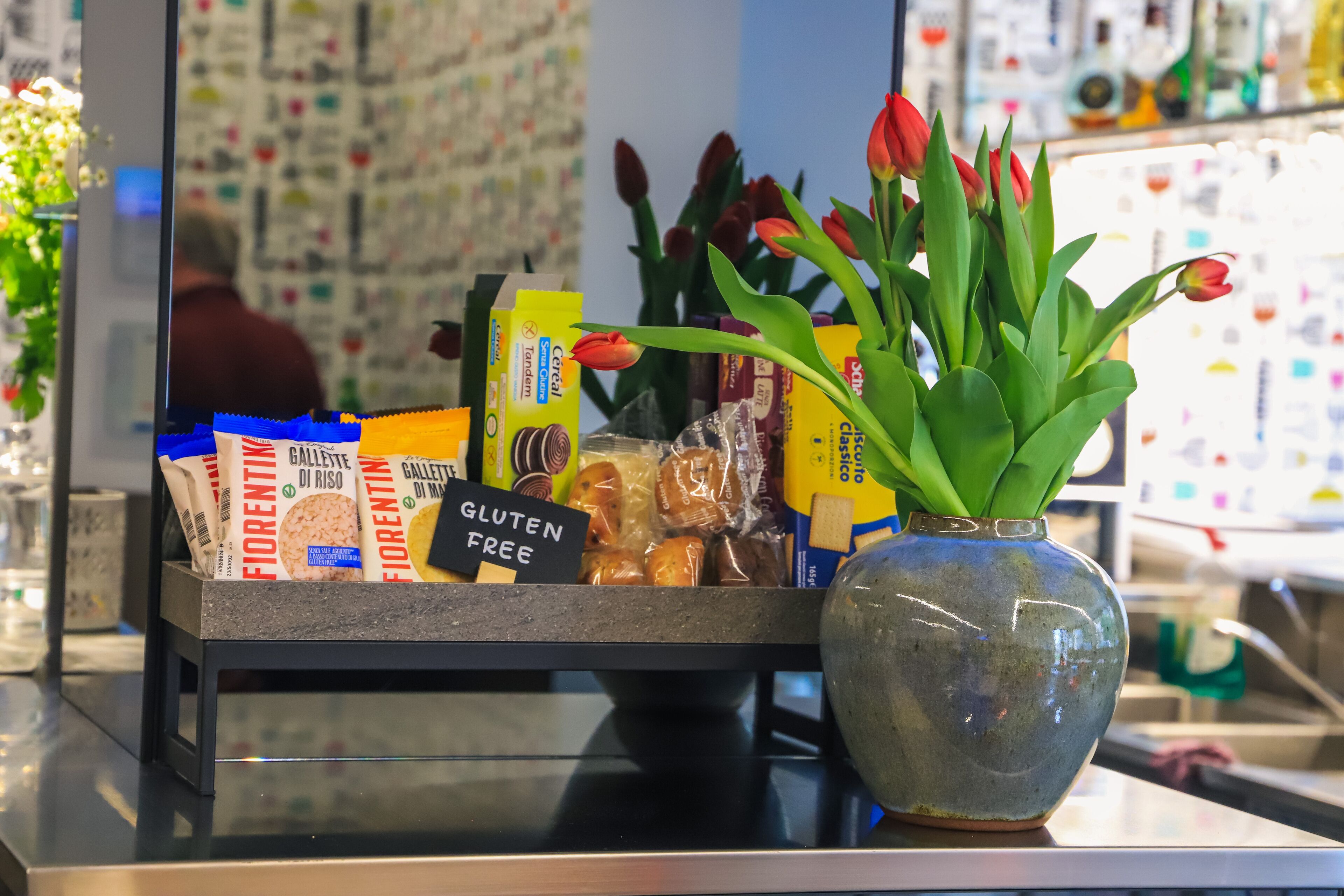 A display of gluten-free products and a vase of tulips on a counter.