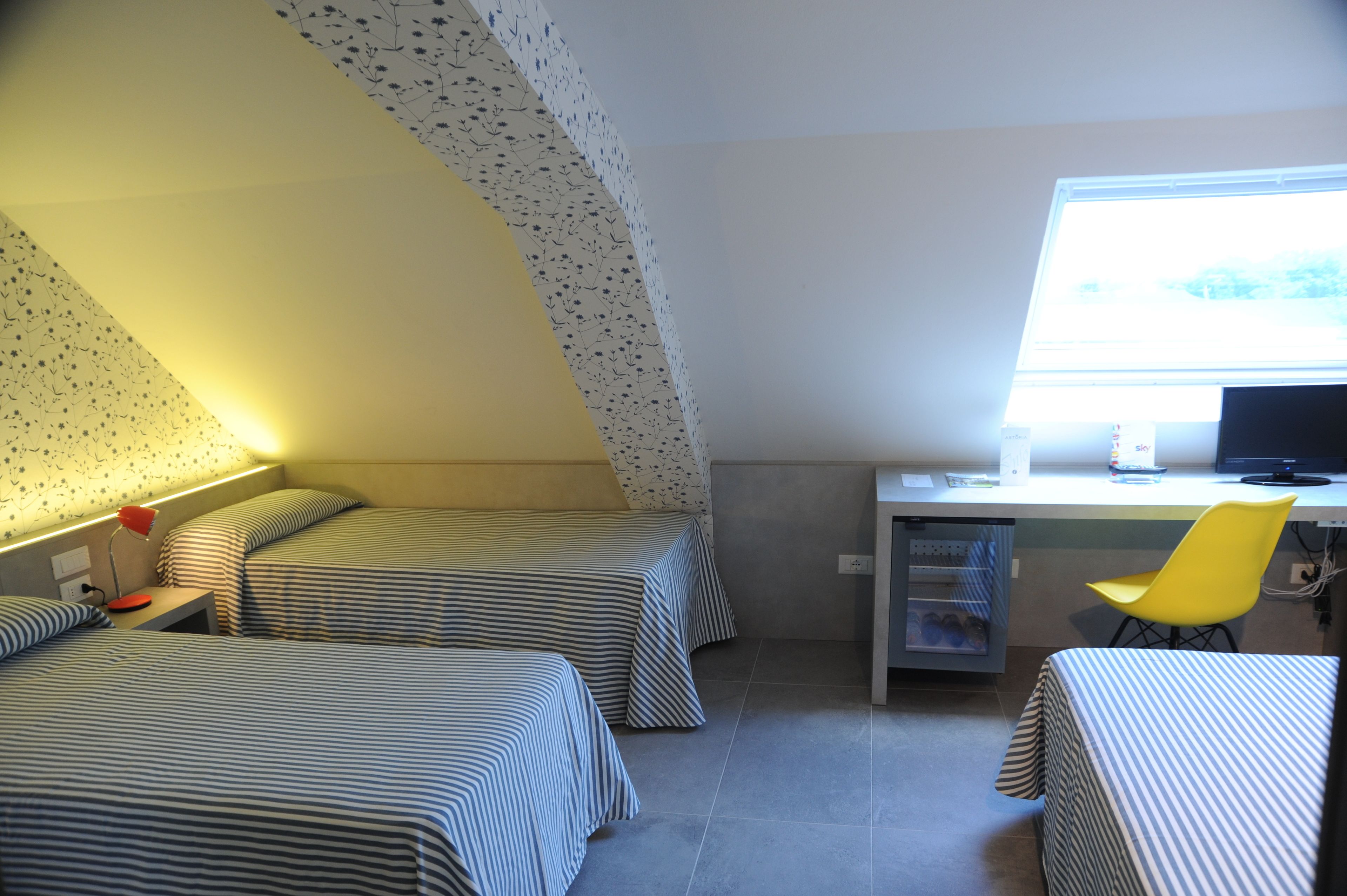 Un dormitorio con dos camas, un escritorio, una silla y una ventana.
