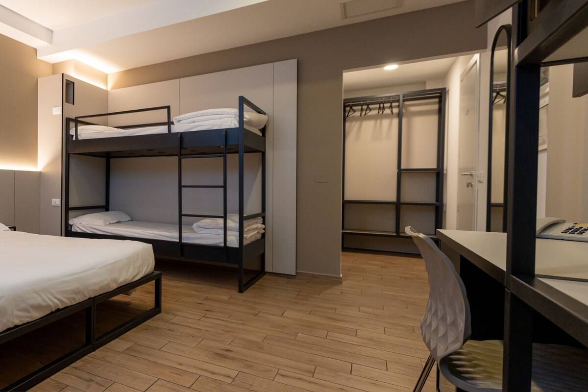 Ein modernes Schlafzimmer mit einem Stockbett, einem Schreibtisch mit Telefon und einem begehbaren Kleiderschrank.