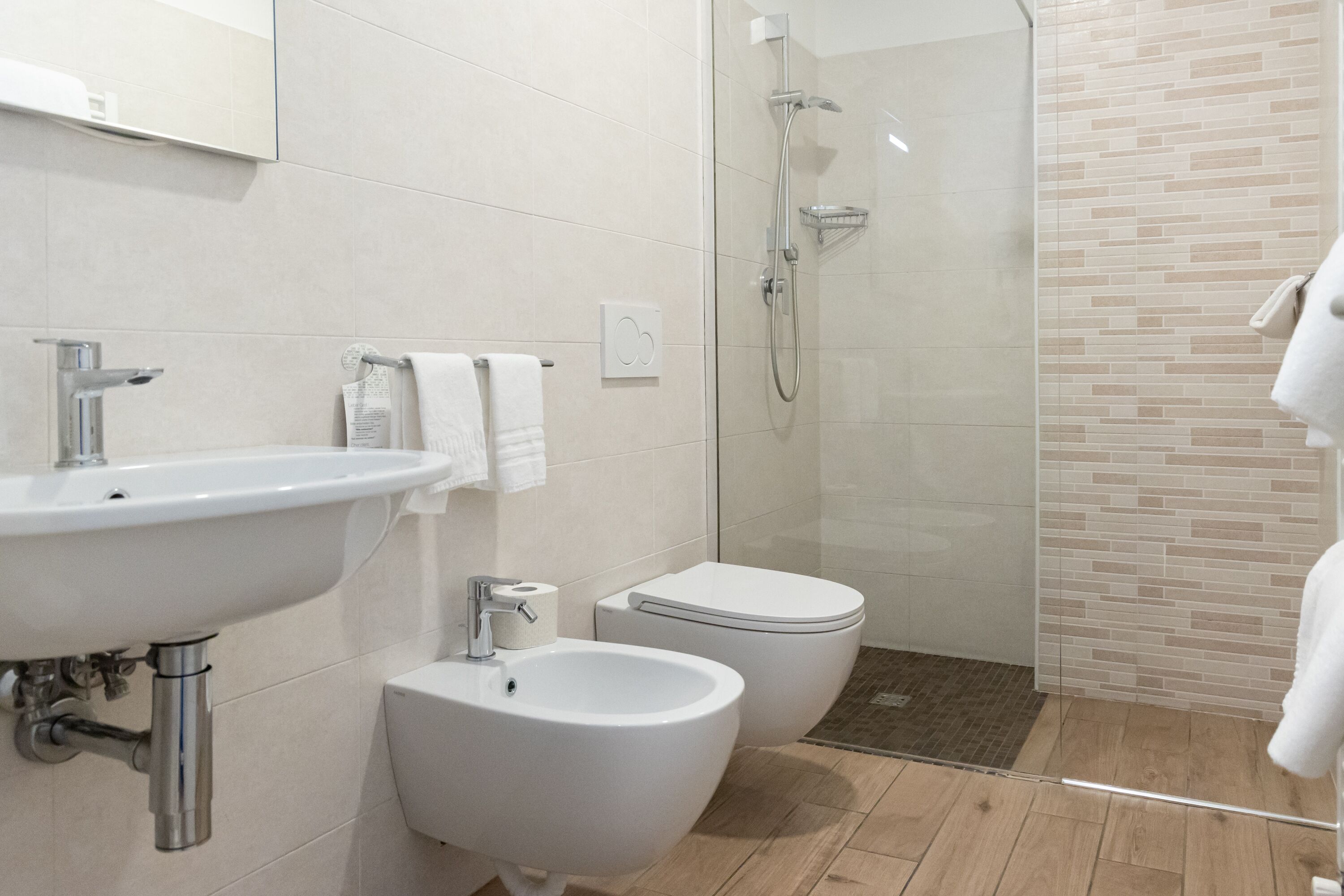 Une salle de bain moderne équipée d’un lavabo, d’un bidet, de toilettes et d’une douche à parois de verre.