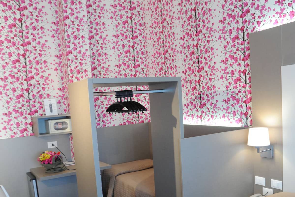 Ein Hotelzimmer mit Bett, Schreibtisch, Stuhl und einem kleinen Tisch mit Lampe.