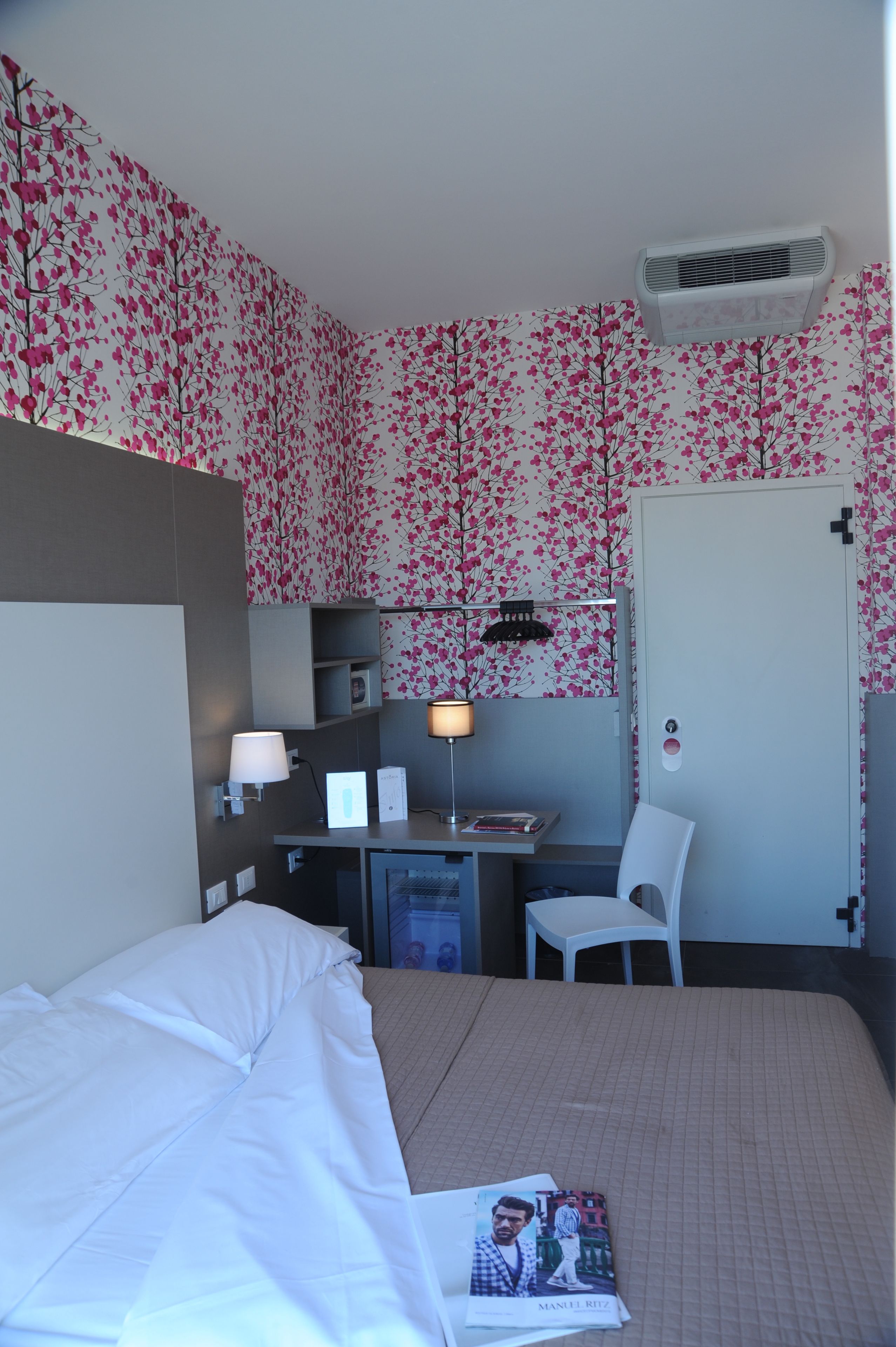 Una habitación de hotel con cama, escritorio, silla y puerta.
