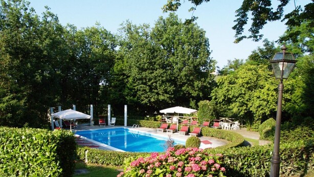 Une piscine entourée d’une végétation luxuriante, un belvédère et des chaises longues.