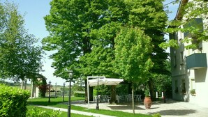Une cour avec un grand arbre, des sièges en plein air et un bâtiment doté de balcons.