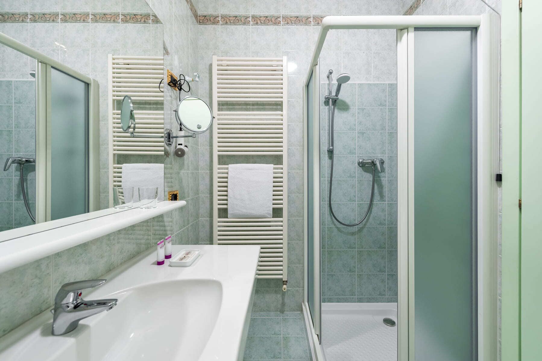 Ein Badezimmer mit Dusche, Waschbecken und Spiegel.