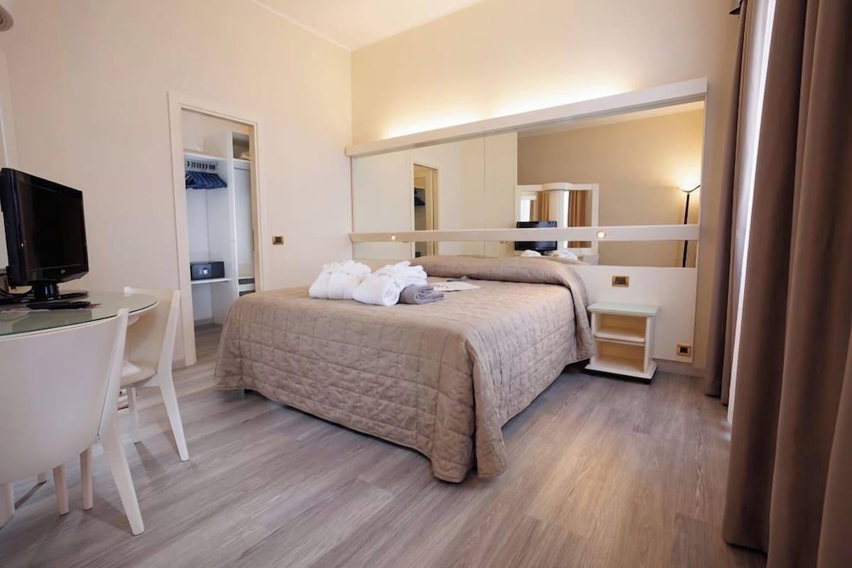 Une chambre d’hôtel équipée d’un lit, d’une télévision, d’un bureau et d’une armoire.