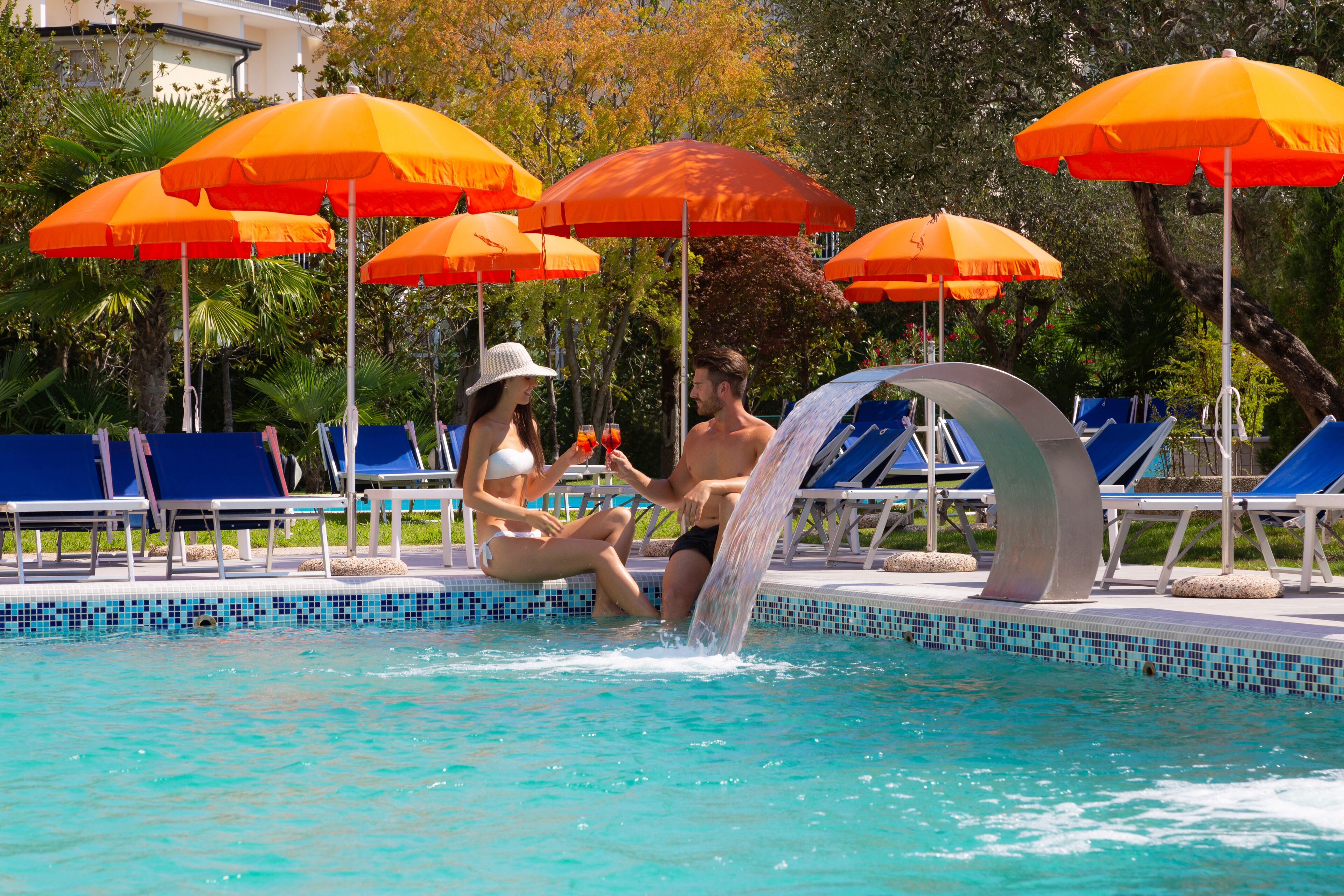 A swimming pool with blue lounge chairs and orange umbrellas.