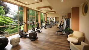 A gym with exercise equipment, large windows, and a view of greenery. - Hotel Savoia Thermae & Spa (Abano Terme)