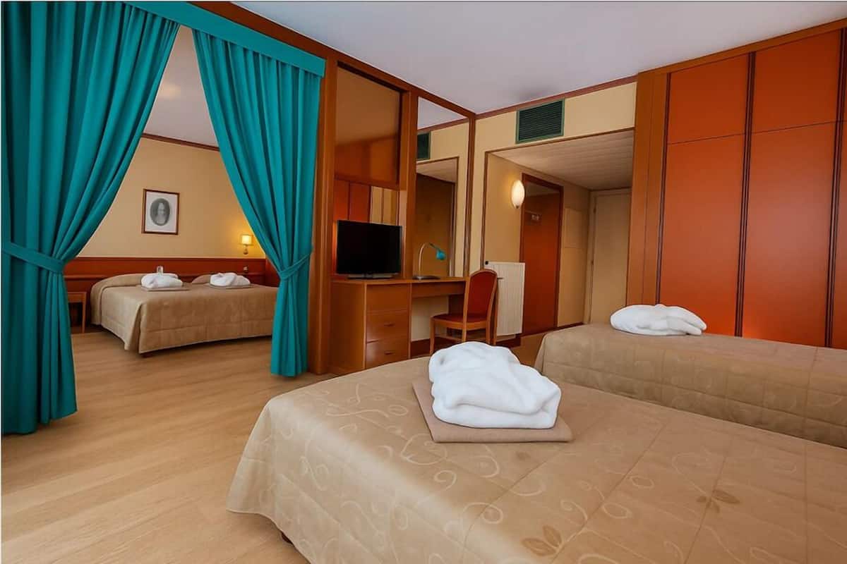 Une chambre d’hôtel avec deux lits, un bureau, une télévision et un miroir.