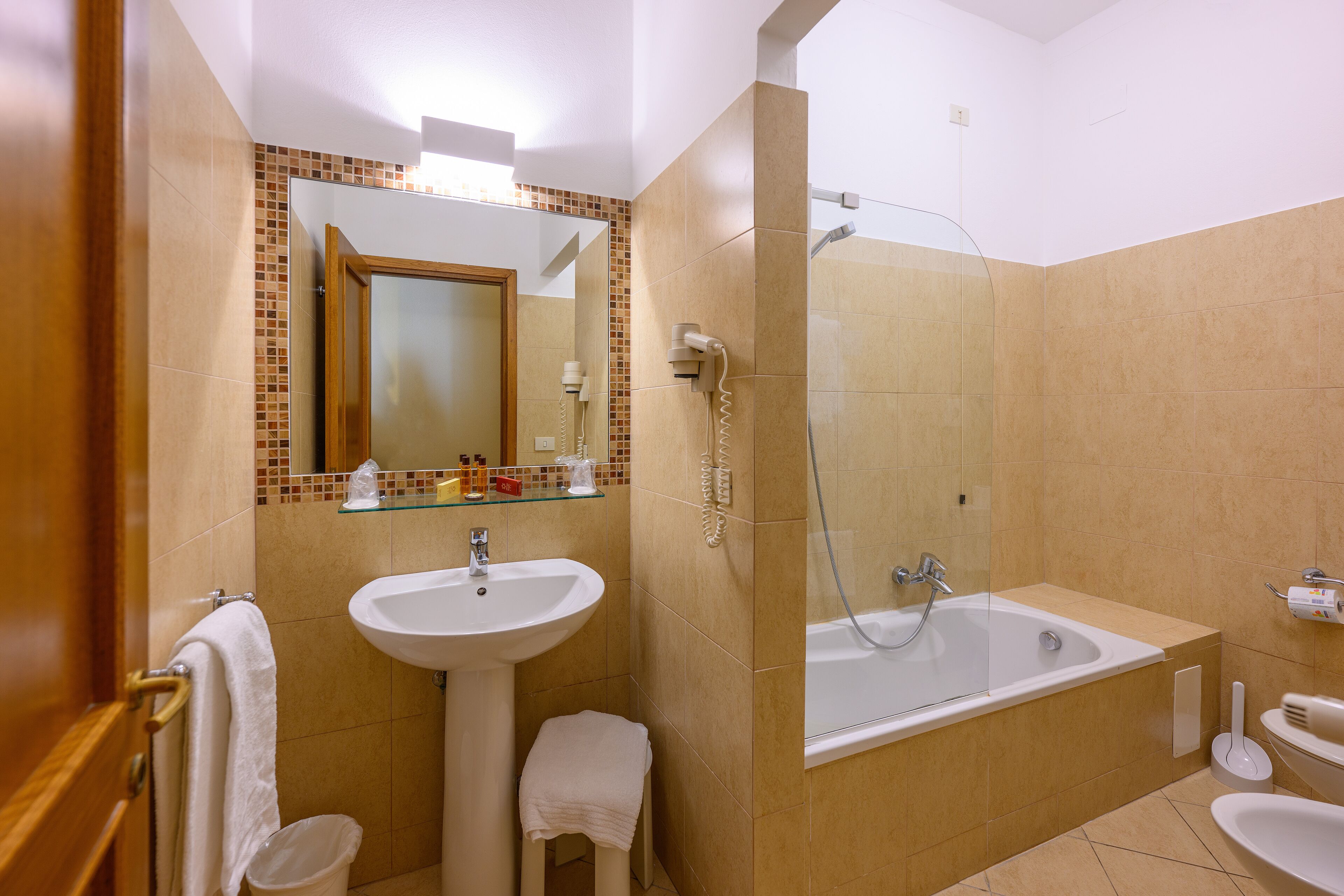 A bathroom with a sink, mirror, and bathtub.