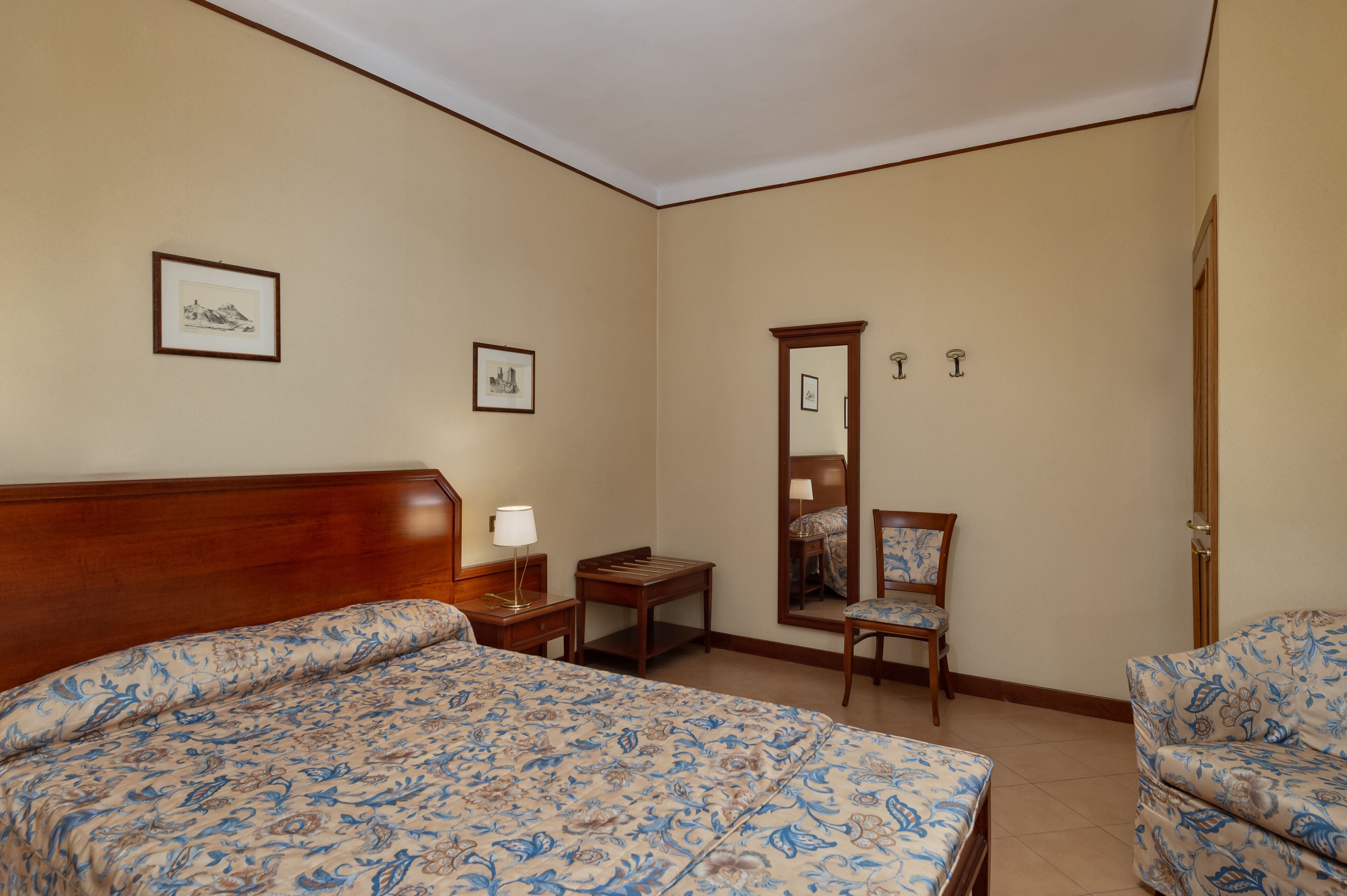 Une chambre d’hôtel avec un grand lit, une chaise, une petite table et un miroir.
