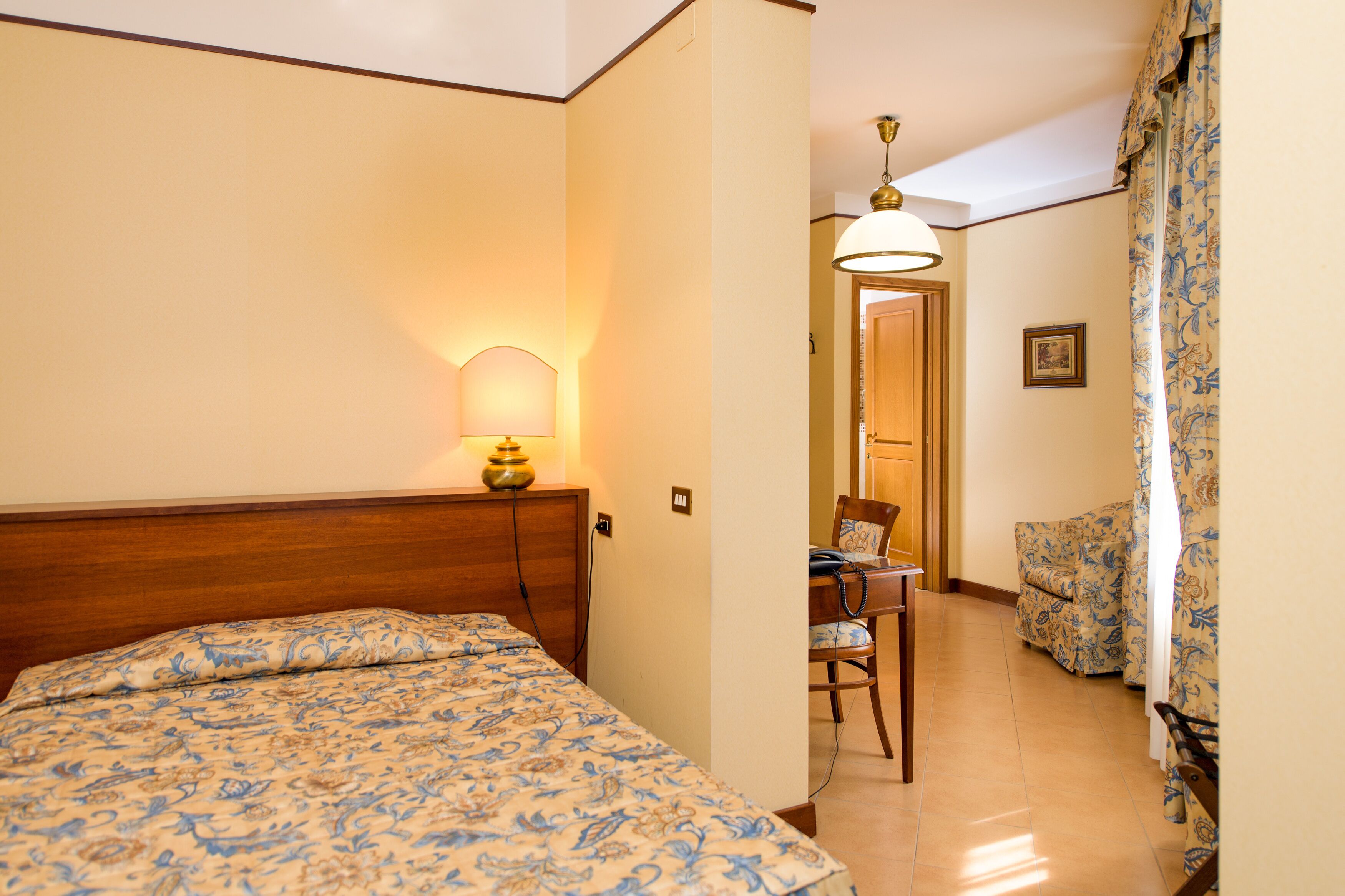 A hotel room with a bed, a desk with a chair, and a sofa.