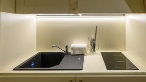 Moderni keittiö, jossa on musta allas, ruostumattomasta teräksestä valmistettu hana ja sisäänrakennettu induktioliesi.