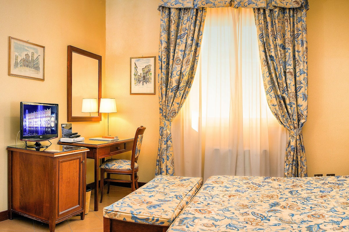 Ein Hotelzimmer mit Bett, Schreibtisch mit Computer, Stuhl und Fernseher.