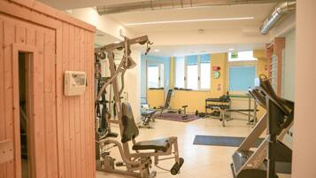 Un gimnasio con varios equipos de ejercicio, incluyendo un banco de pesas, mancuernas y una cinta de correr.
