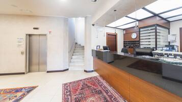 A reception area with a reception desk, a staircase, and a clock on the wall.