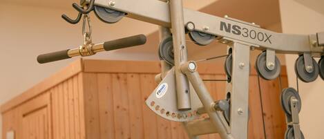 Un gimnasio con una bicicleta estática y máquinas de pesas, incluyendo una prensa de banca y una prensa de piernas.