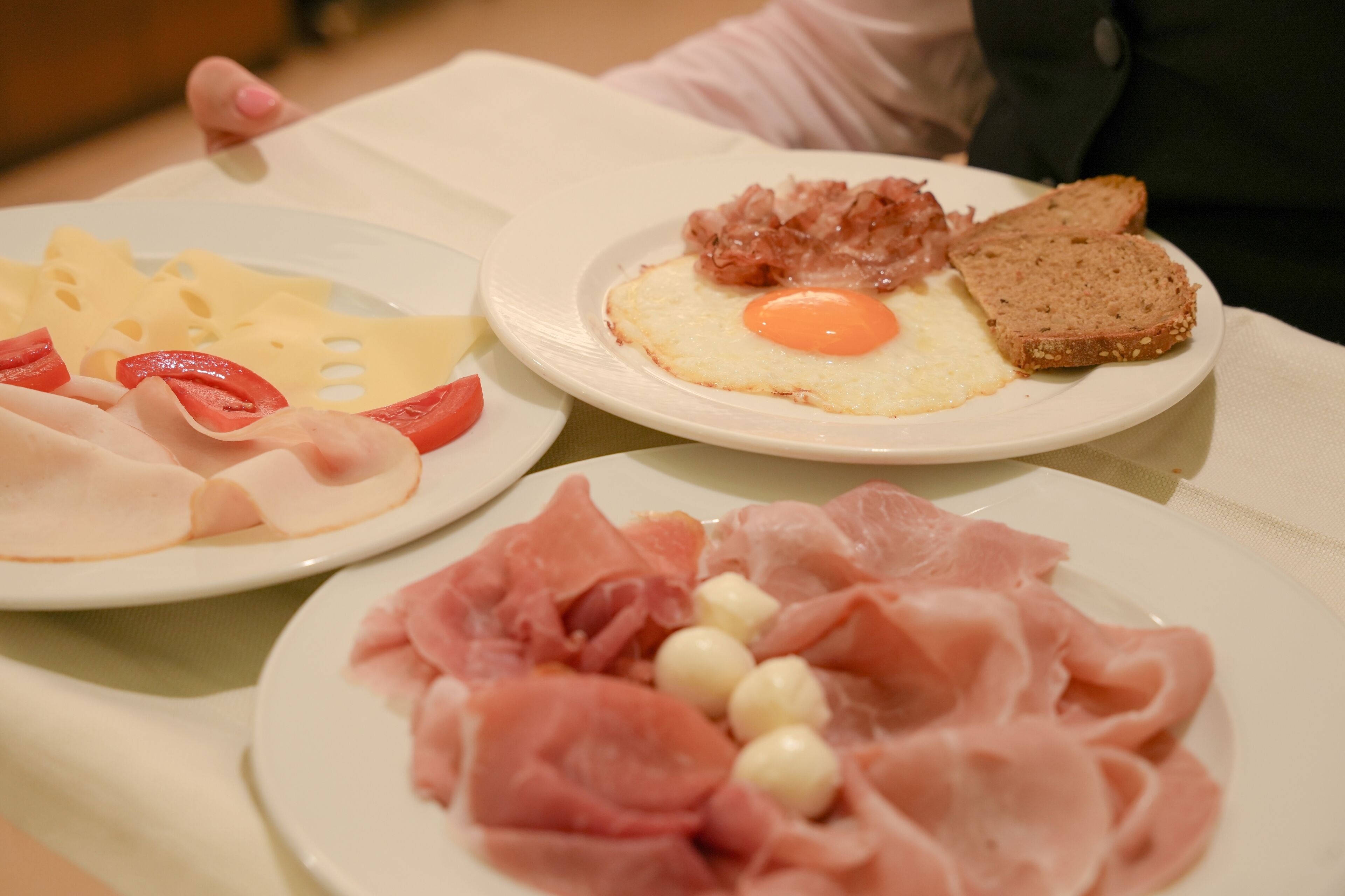 Un plato de desayuno con jamón, queso y un huevo frito.