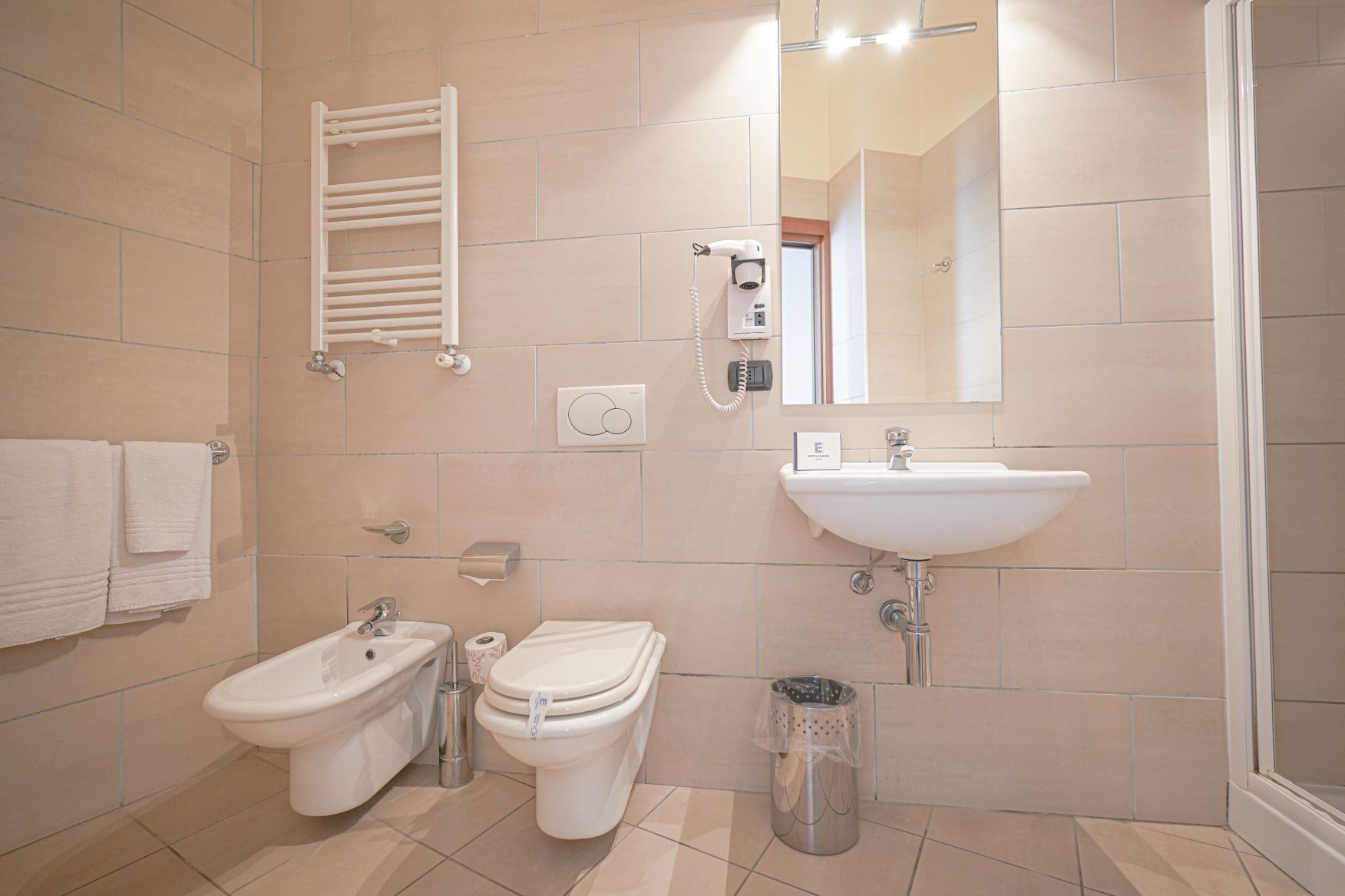 Une salle de bain moderne équipée d’un bidet, de toilettes, d’un lavabo et d’un porte-serviettes.