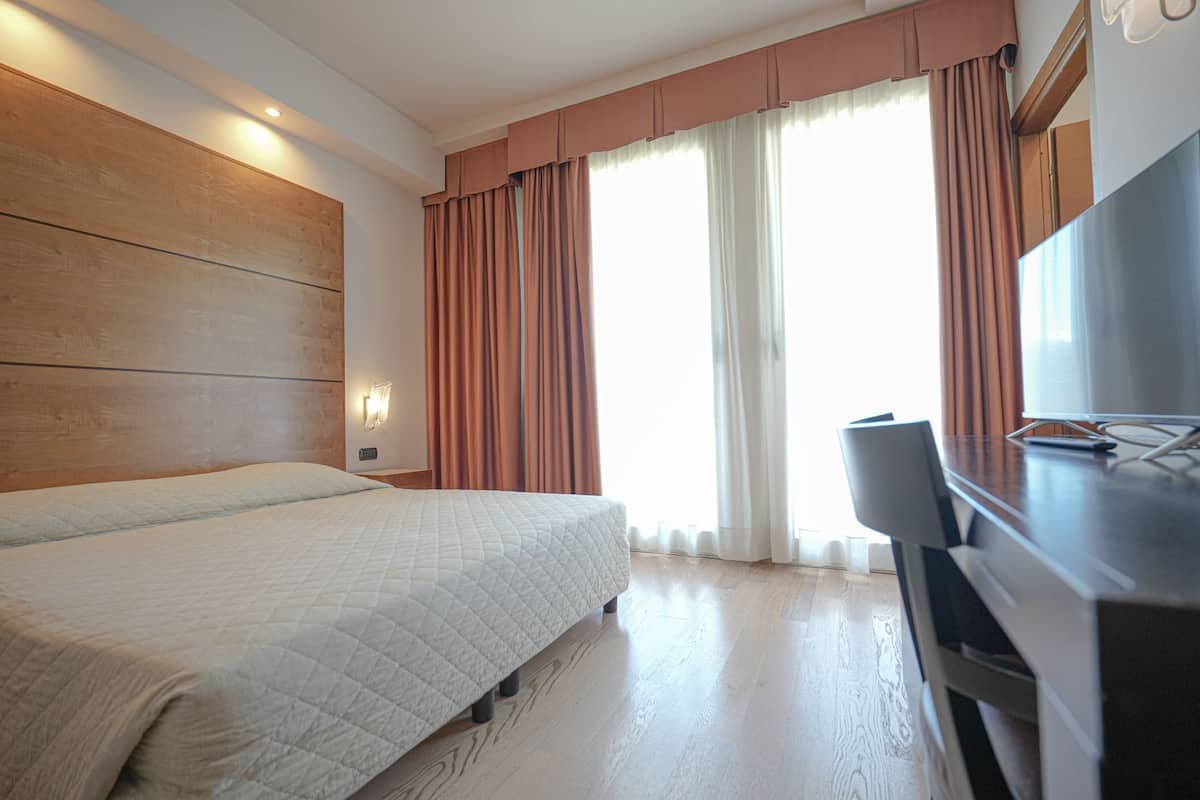 A hotel room with a bed, a desk, and a TV.
