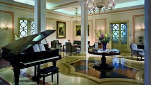 A grand lobby with a grand piano, elegant chandeliers, and classic decor.