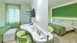 A hotel room with a curved white desk, two green chairs, a bed with a green headboard, and a television mounted on the wall. - Hotel Londra (Alessandria)