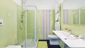 Un baño moderno con ducha envuelta en vidrio, un lavabo blanco y un diseño de pared a rayas.