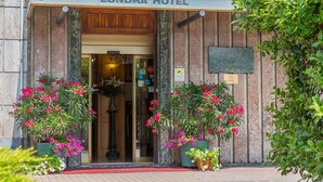 The entrance of the Londra Hotel with a sign above the door and a flower arrangement at the entrance. - Hotel Londra (Alessandria)