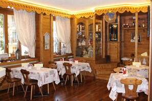 Un restaurante acogedor con interiores de madera, mesas con manteles blancos y una variedad de adornos.