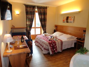 Una habitación de hotel con cama, mesita de noche, lámpara y vistas al exterior a través de la ventana.