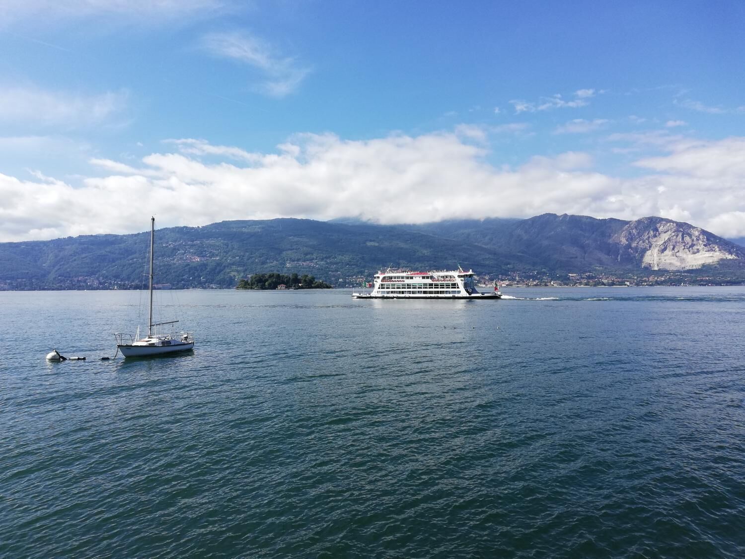 Un lago con un velero y un ferry.