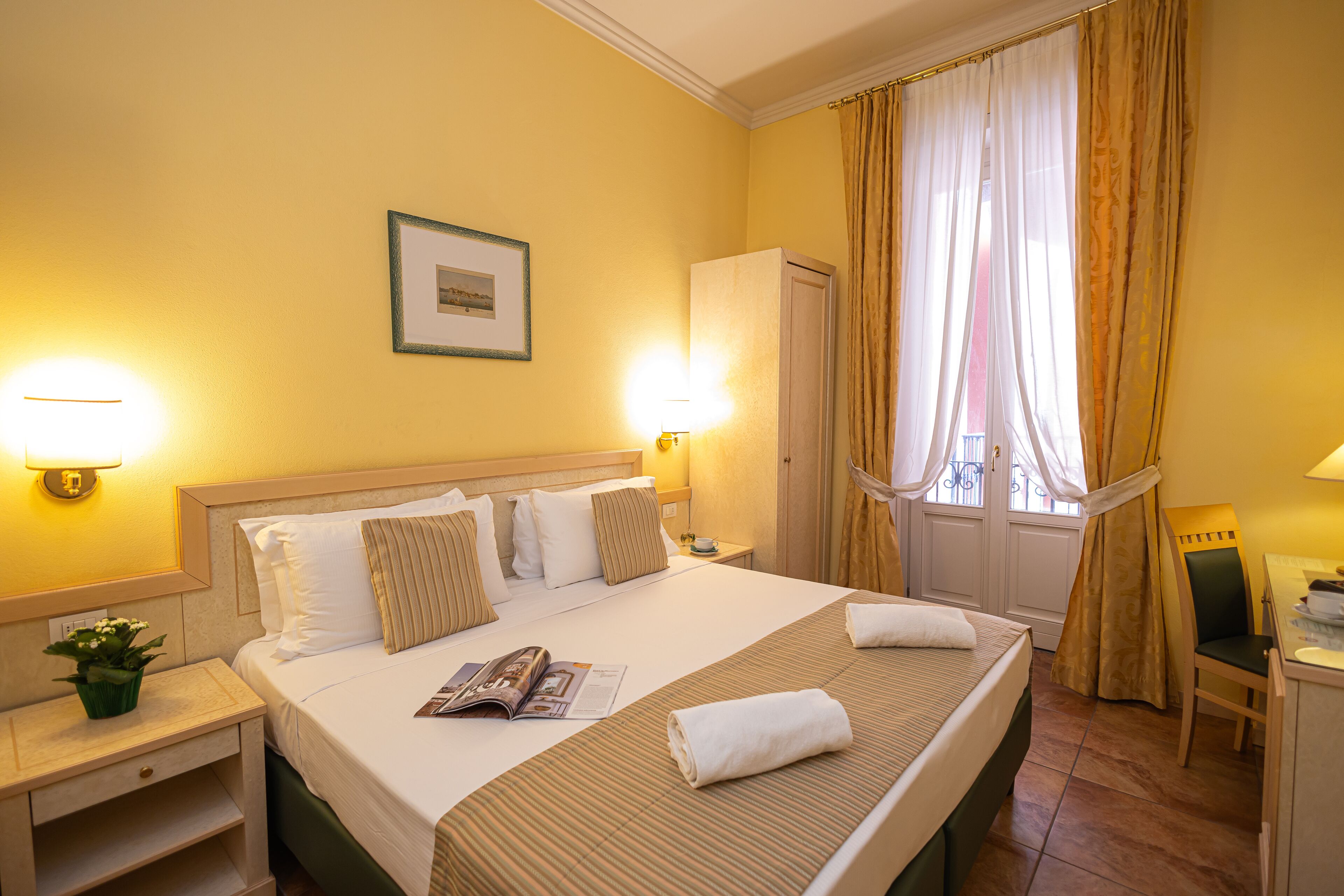 A hotel room with a large bed, two bedside tables, a desk, and a chair.