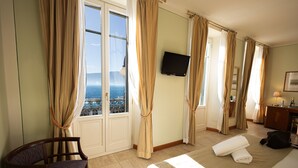 Ein Hotelzimmer mit Bett, Sessel, Fernseher und Meerblick.