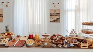 Ein reichhaltiges Buffet mit verschiedenen Speisen, darunter Früchte, Backwaren und Getränke.