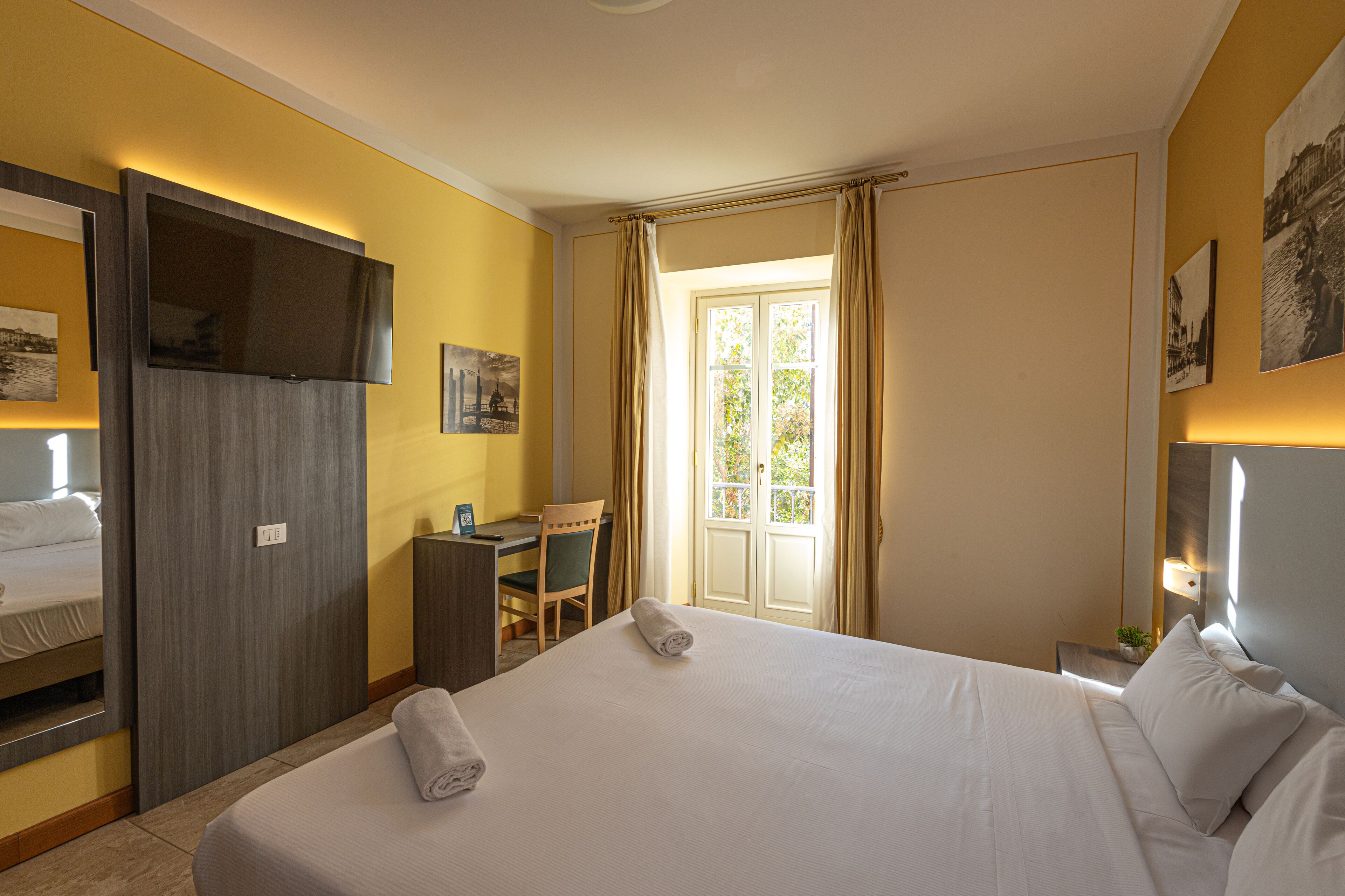 A hotel room with a bed, a desk, a chair, and a window with curtains.