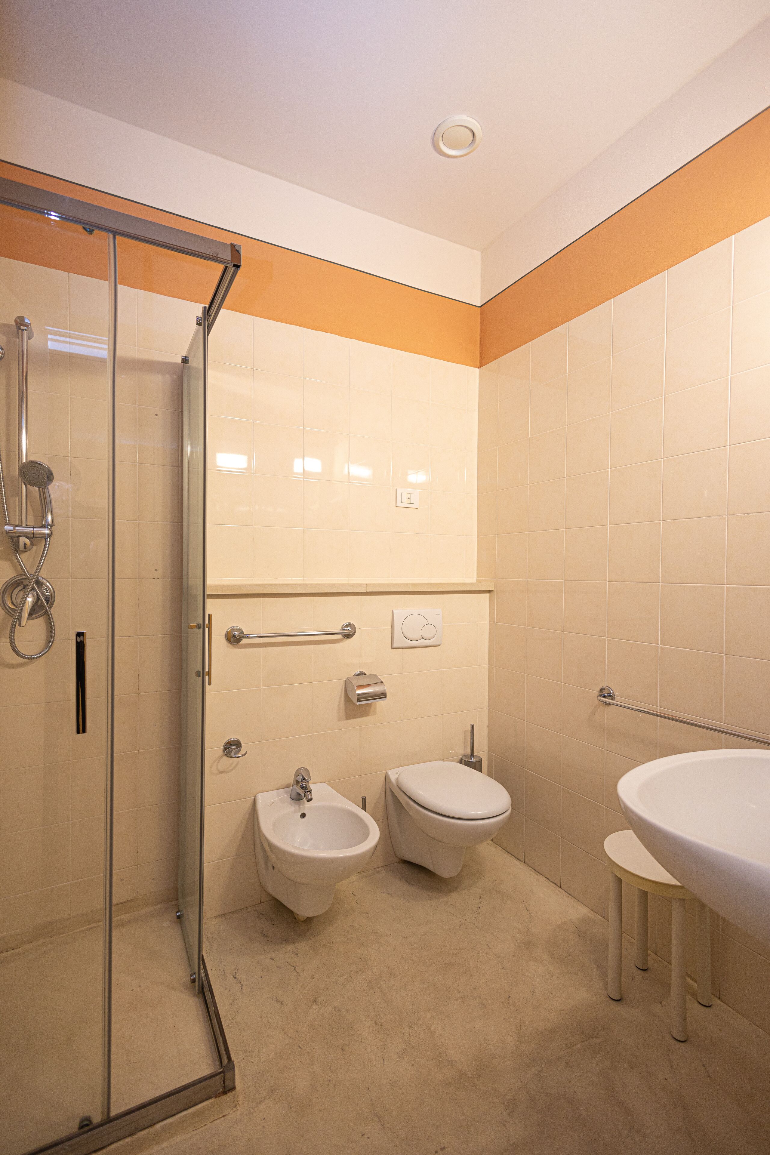 Un baño con cabina de ducha de vidrio, un bidé, un inodoro y un lavamanos.