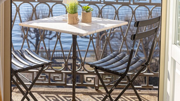 Ein Balkon mit Tisch und Stühlen, Blick aufs Meer und einer dekorativen Geländer.