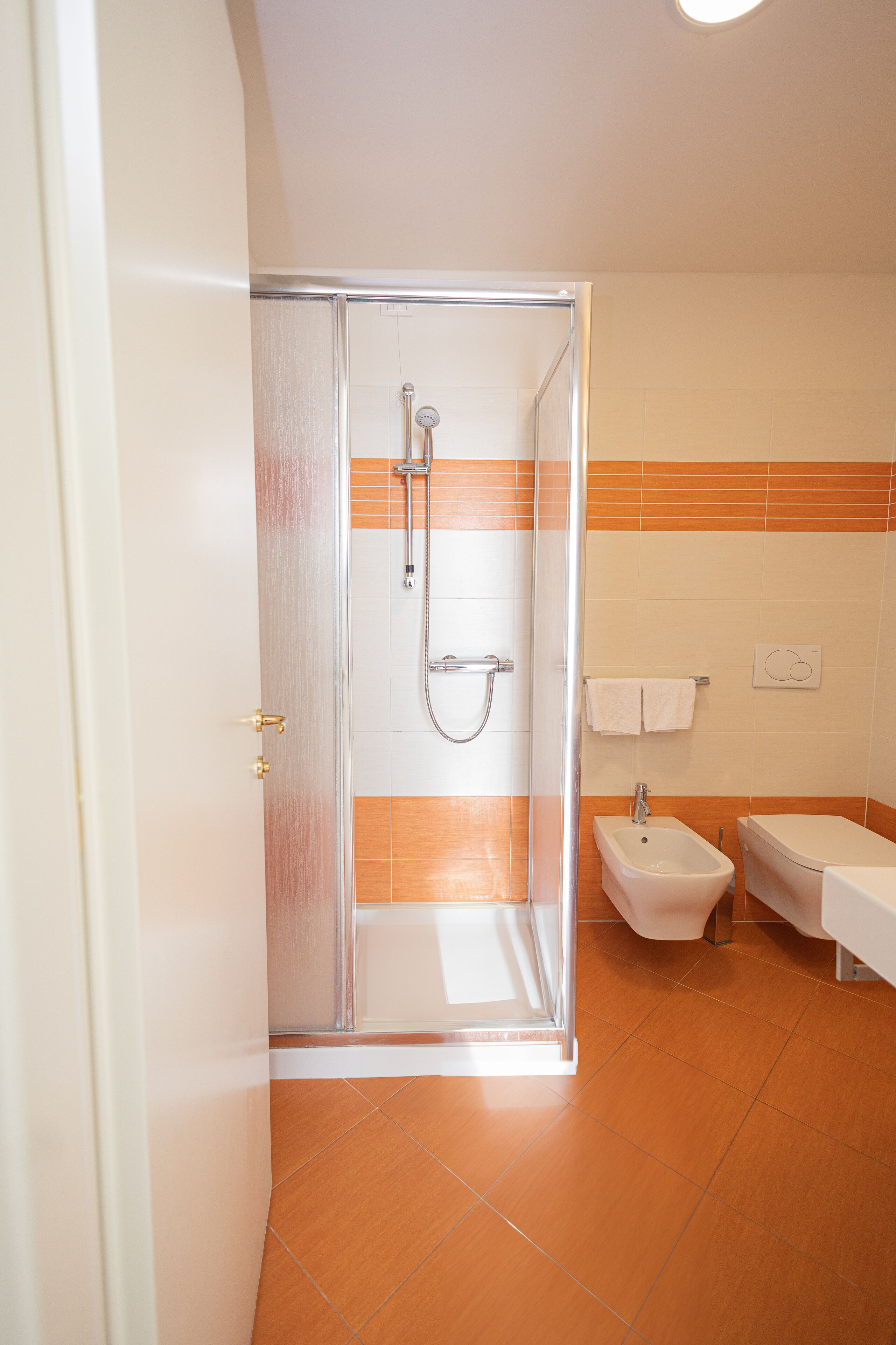 A bathroom with a glass-enclosed shower, a bidet, and a bathtub.