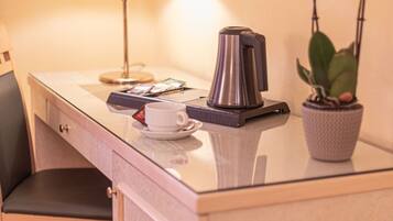 A small, compact workspace with a desk, chair, lamp, coffee maker, and a potted orchid.