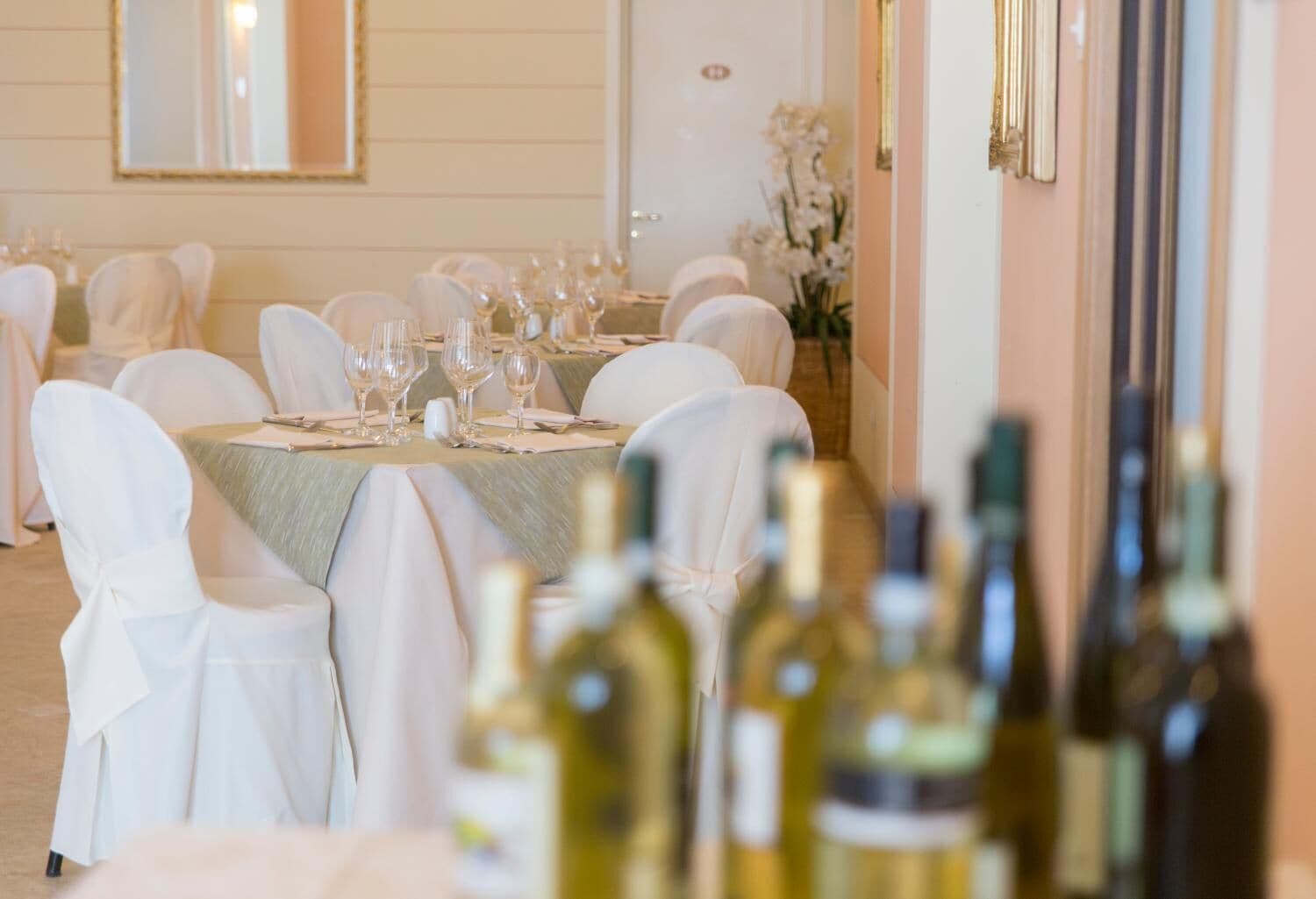 A banquet hall with round tables set for a formal event, each with white tablecloths and glassware.